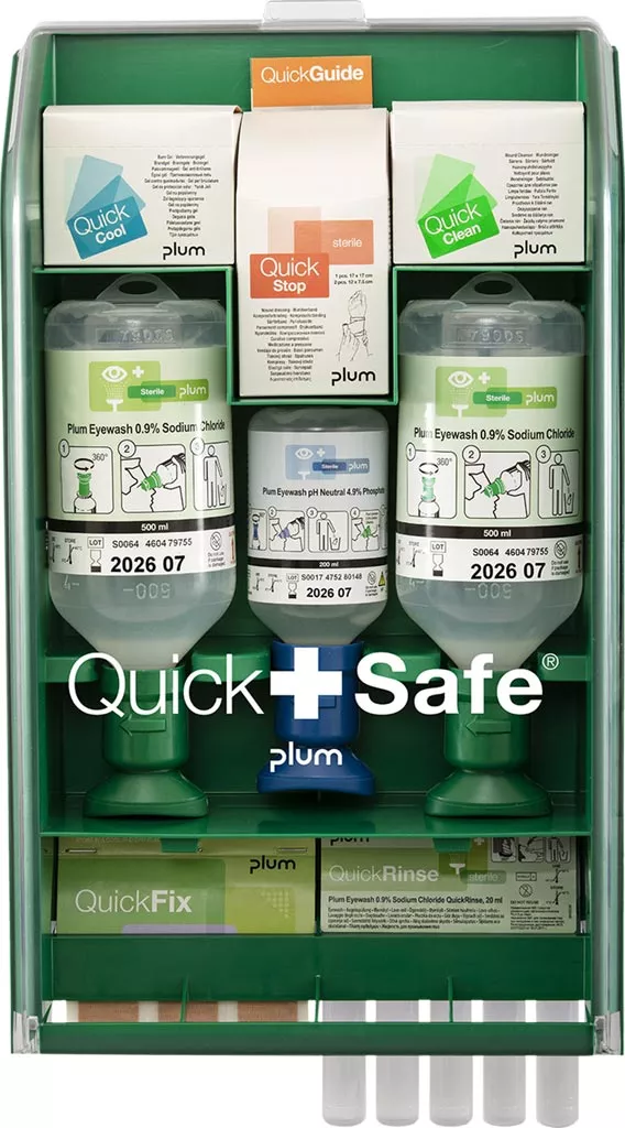 Stacja pierwszej pomocy QuickSafe® Complete zawiera różne opatrunki, plastry, zimny spray oraz środki do czyszczenia oczu i oparzeń, umieszczone w wyraźnie oznakowanych pojemnikach dla łatwej identyfikacji.