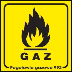 Znak bezpieczeństwa o żółtym tle z czarną grafiką płomienia i napisem „GAZ” w dolnej części. Pod spodem dodatkowy napis „Pogotowie gazowe 992”.