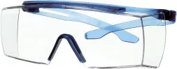 Okulary ochronne mają przezroczyste, duże soczewki oraz niebieskie elementy na zausznikach i nosku. Design zapewnia szerokie pole widzenia.